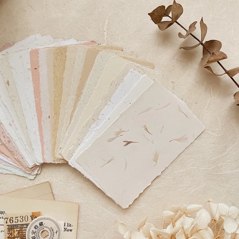 Collection of handmade papers with natural textures on a beige surface.