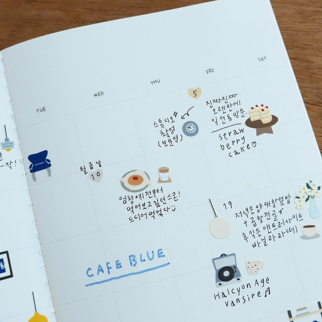 Notebook with stickers and text on a wooden surface, from the Café Blue Sticker Sheet