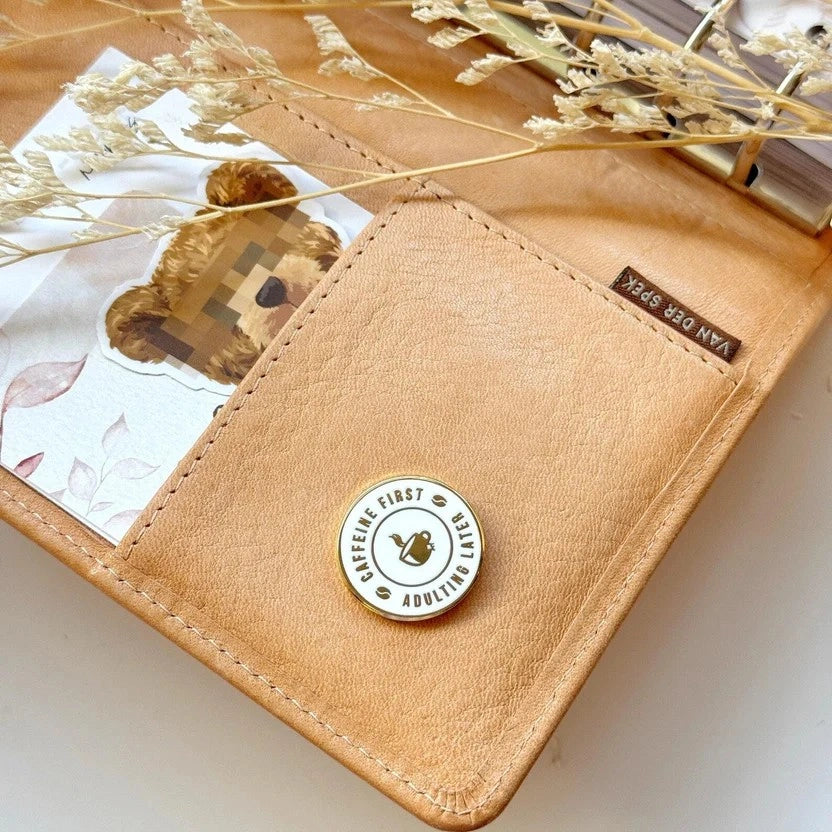 Caffeine First Planner Magnetic Charm on a brown leather cardholder styled with dried plants