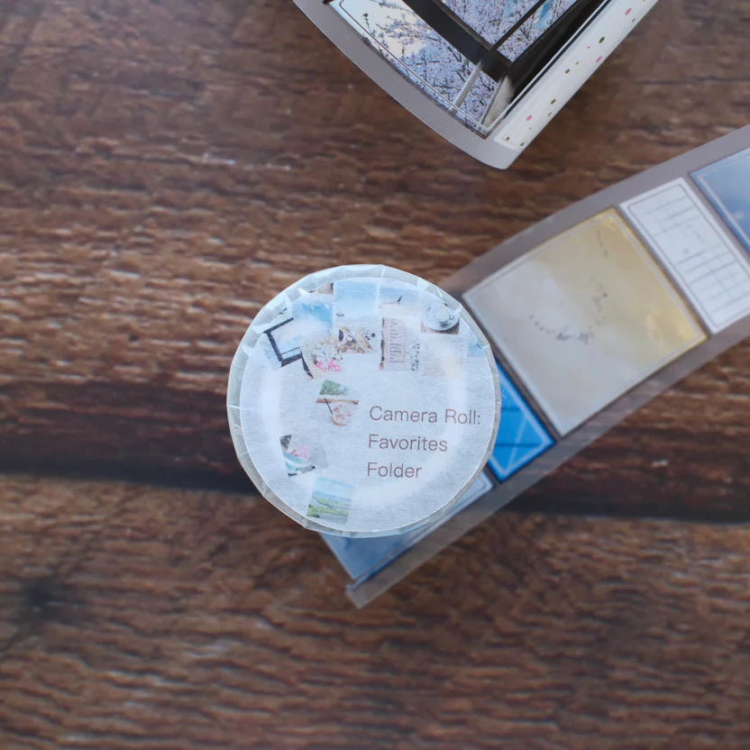 Round tin labeled Camera Roll Favorites Folder PET Tape by rabch.jpg on a wooden surface
