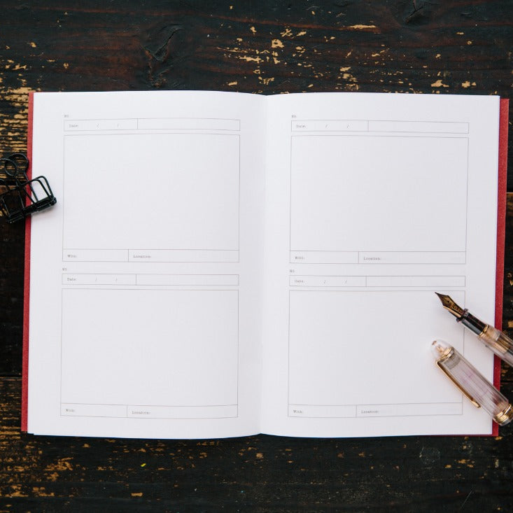 Open Card Folder Notebook with a pen and ink bottle styled alongside on dark wood