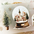 Decorative sticker set with a snow globe, Christmas tree, and houses on a white background
