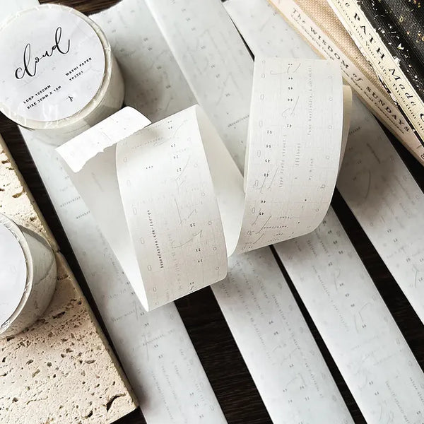 Rolls of Cloud Washi Tape with retro programming-style text on a textured surface, close-up view