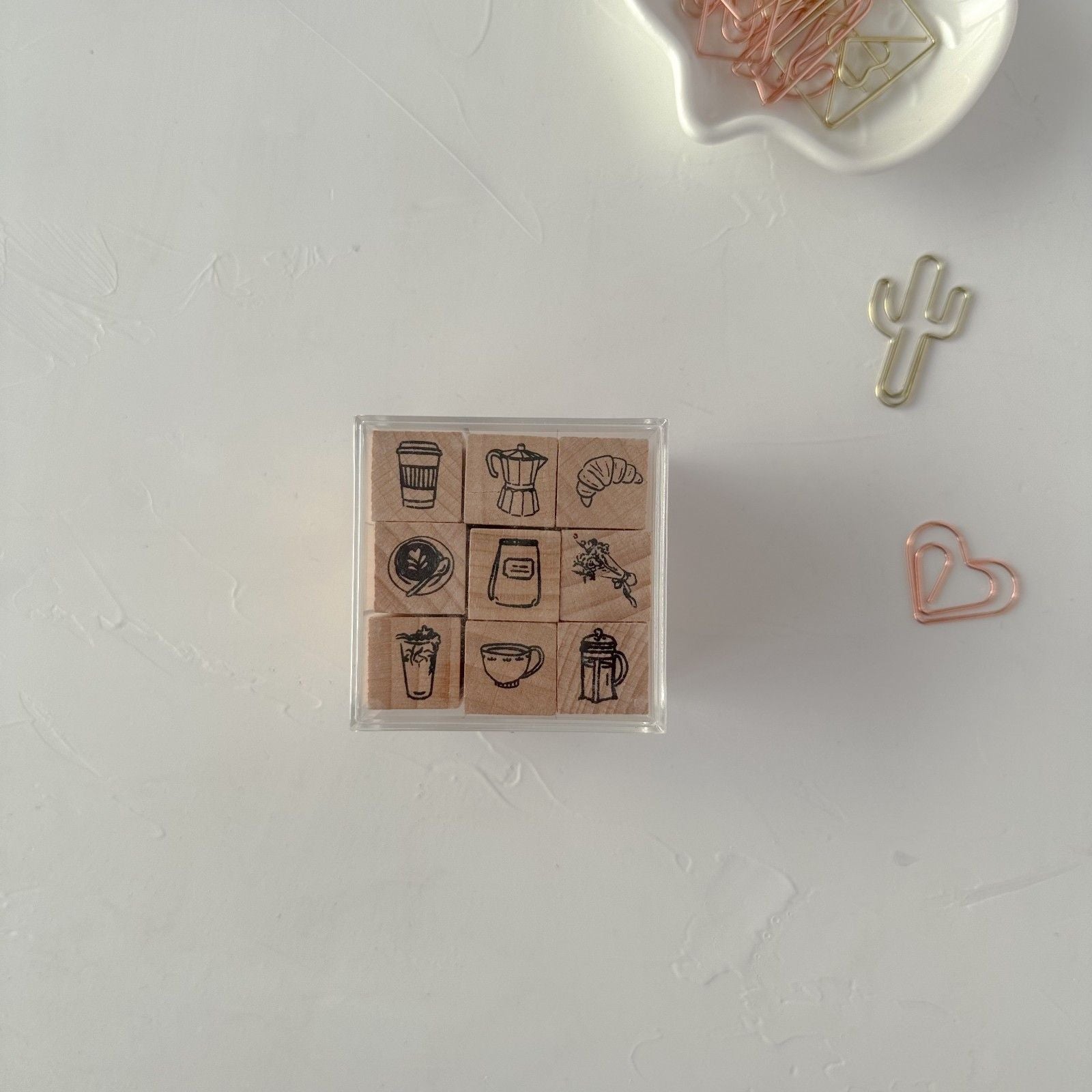 Set of rubber stamps with coffee-themed designs on a white surface with paper clips.