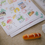 Colorful stationery items including a bread-shaped eraser on a textured surface.