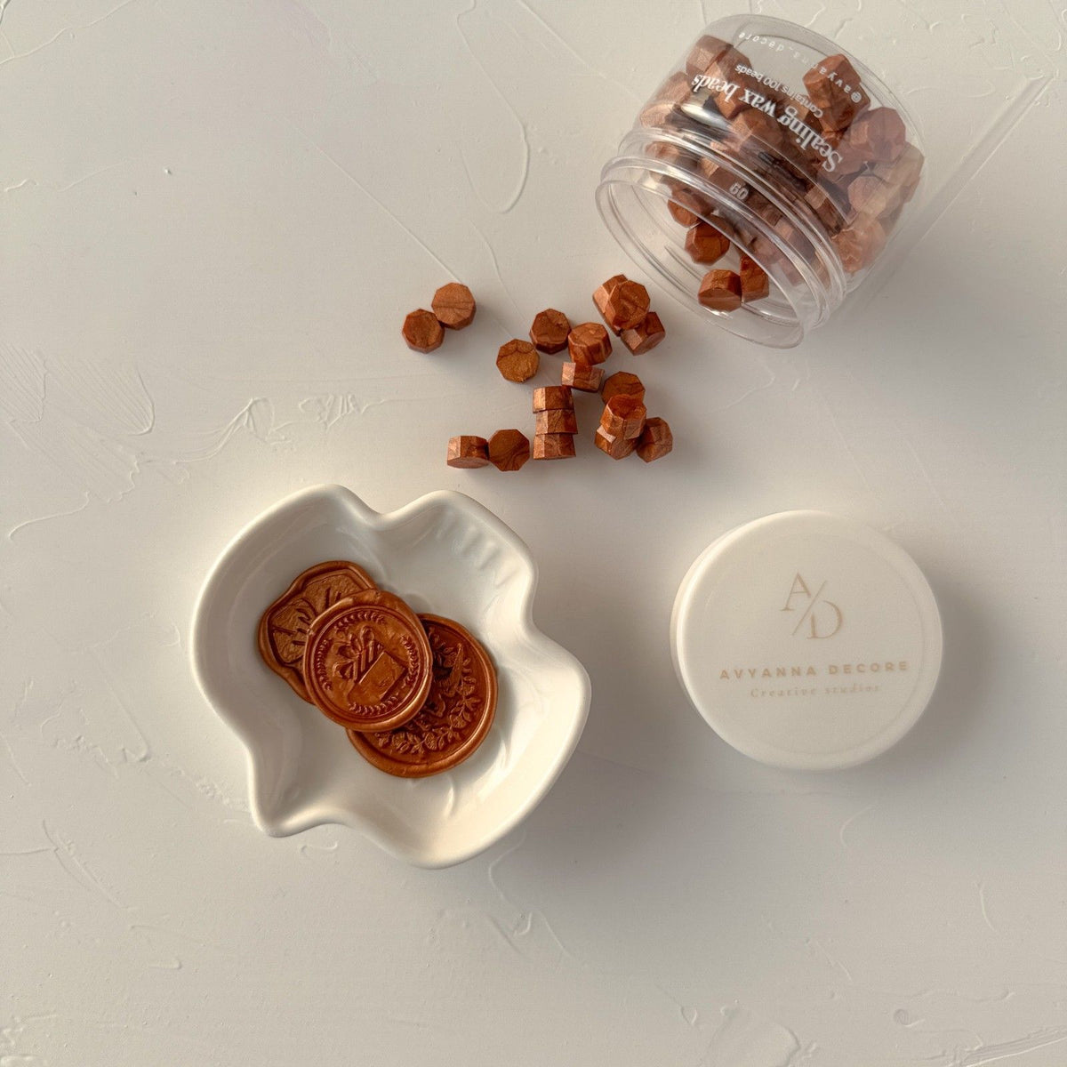 Container of hexagonal Copper Wax Beads in a warm metallic tone with its white lid on a grey background