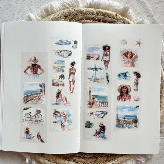 Open book styled with Coastal Living PET Tape stickers of beachgoers and coastal landscape scenes