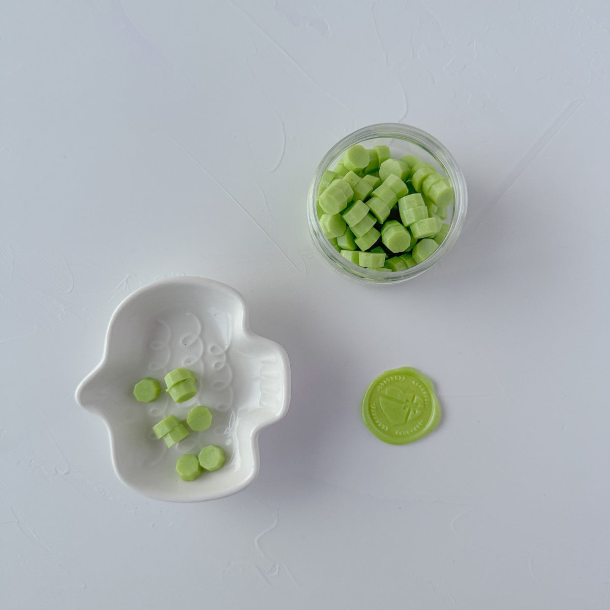 Minty green Cucumber Cooler Wax Beads scattered beside a small dish and container, flat lay on white