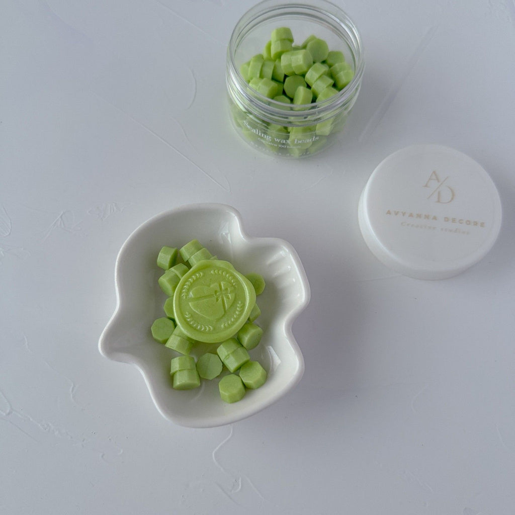 Green wax melts in a white dish and jar on a light gray background