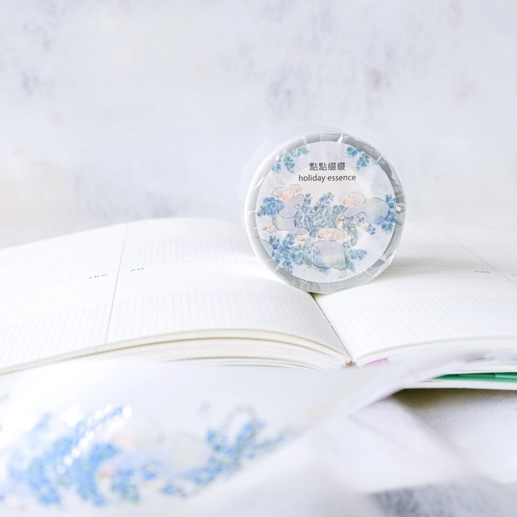 Holiday Essence PET Tape by Dodolulu — 'holiday essence' PET tape roll on a floral book, for journaling