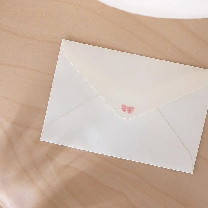 White envelope with a pink butterfly design on a beige surface, from the Deco 13 Sticker Sheet