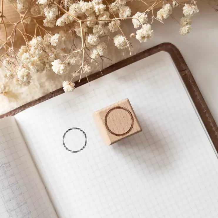 Deco Ring Rubber Stamp on a notebook with its ornamental ring print and dried flowers behind