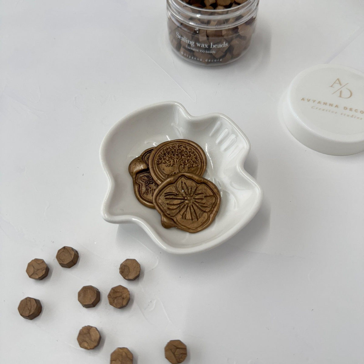 Round Desert Shrub Wax Beads in muted earthy tones scattered beside a white heart-shaped dish, flat lay view