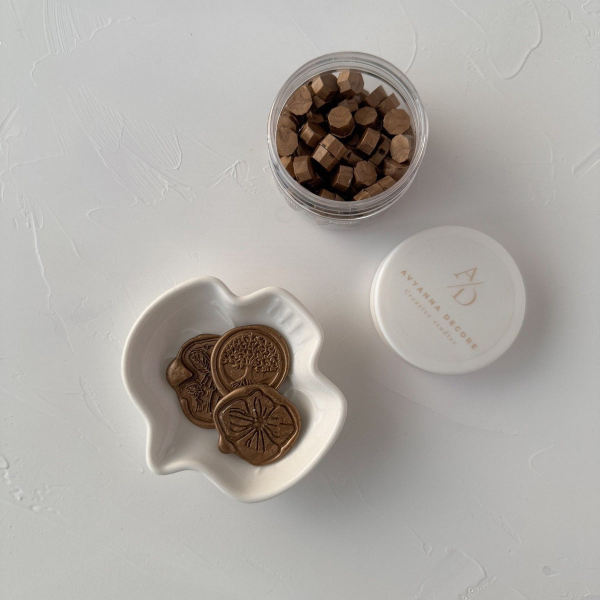 Desert Shrub sealing wax beads in a small white dish with the full container and lid on a light grey backdrop