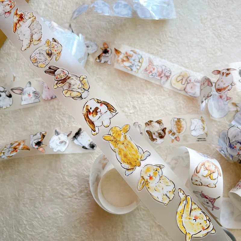 Rolls of Cute Rabbit Ji A34 PET Tape with playful rabbit designs on a textured surface