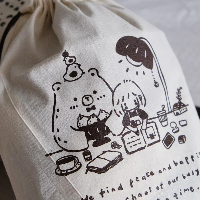 Brown One Stamp at a Time Drawstring Pouch in beige with black illustrations on a white backdrop