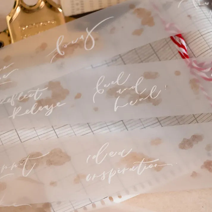 Dream Time Calligraphy PET Tape script and gold foil design on clear packaging, checkered backdrop