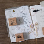 Open notebook with stamps and a pen on a wooden surface