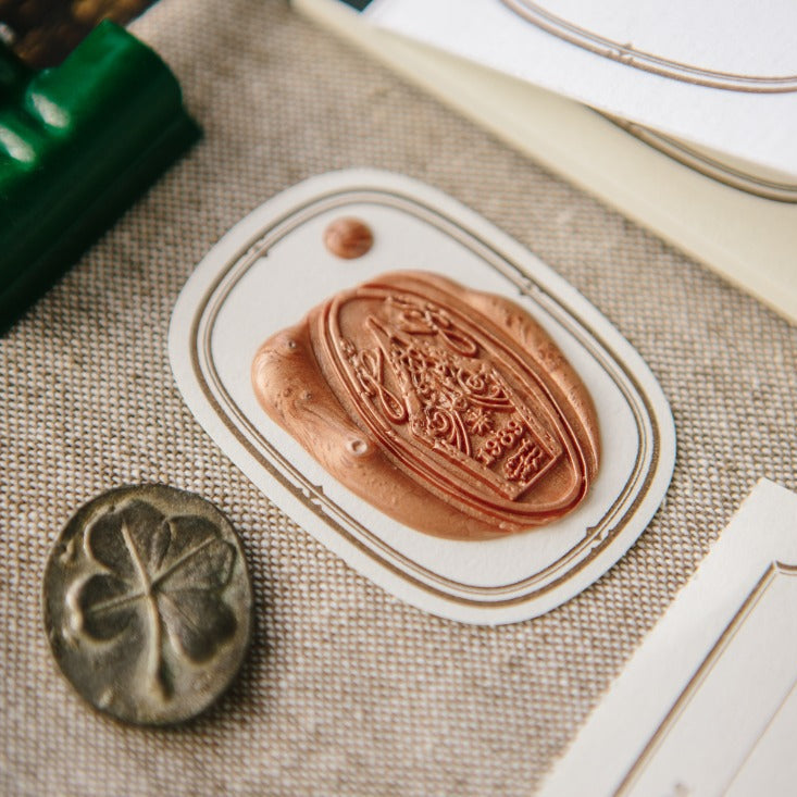 Two vintage-style Ellipse Label Letterpress Book labels on fabric with a green paper clip