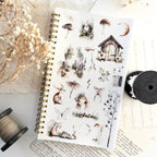 Notebook with nature-themed stickers on a textured surface with decorative elements.