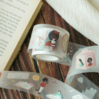 Decorative tape with illustrations of a cat and camera on a wooden surface with an open book.
