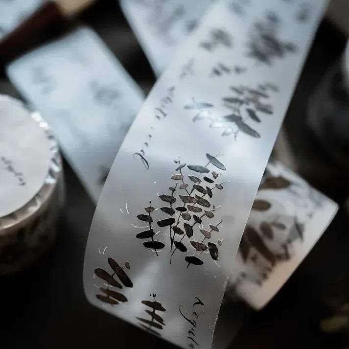 Close-up of an Eucalyptus Matte PET Tape roll showing its transparent printed design on a dark backdrop