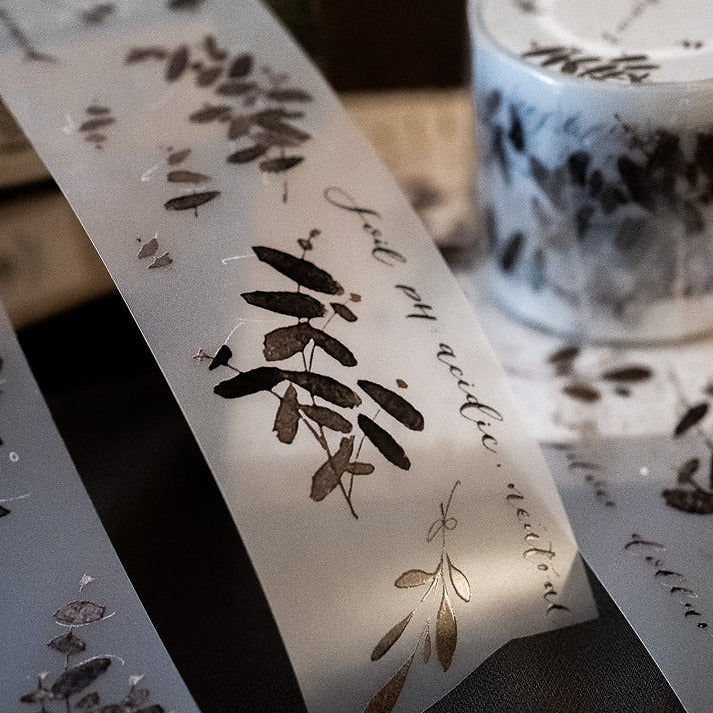 Translucent Eucalyptus Matte PET Tape sheet with leaf motifs and text placed on a dark moody surface
