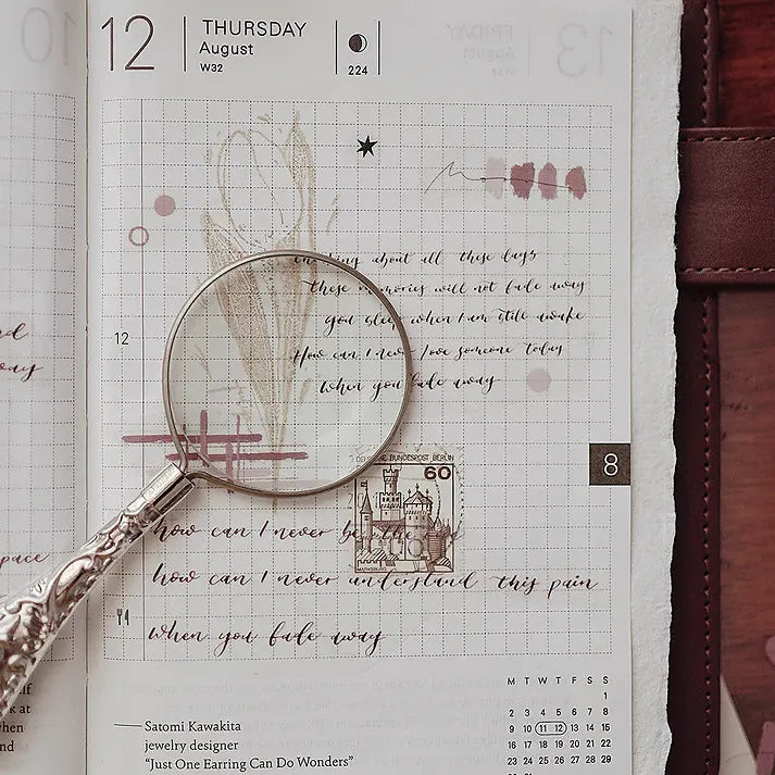 Fade Away PET Tape on a planner page viewed through a magnifying glass, styled close-up detail shot