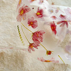 Floral ribbon with pink flowers and green leaves on a textured beige background