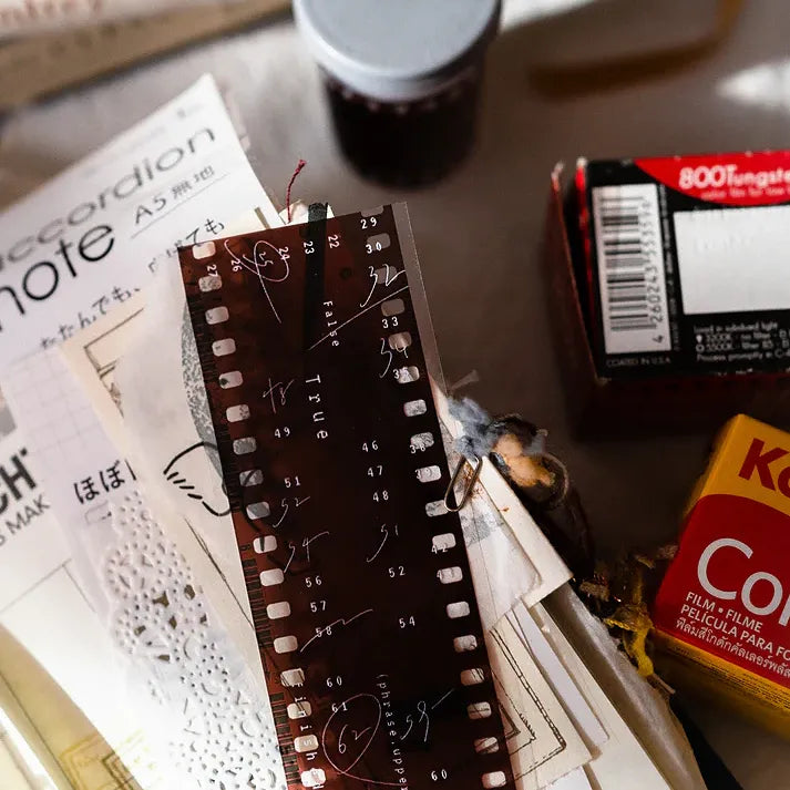 Detail shot of Film PET Tape strips layered with vintage-style paper items on a textured craft surface