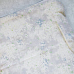 Close-up of a textured white surface with small green and blue specks