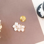 Floral pin and gold button on a pink surface