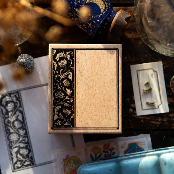 Decorative wooden box with intricate black floral design on a table with cards and other decorative items.