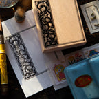 Decorative wooden box with floral patterns on a surface with stationery items.