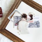 Wooden picture frame with decorative items on a white surface