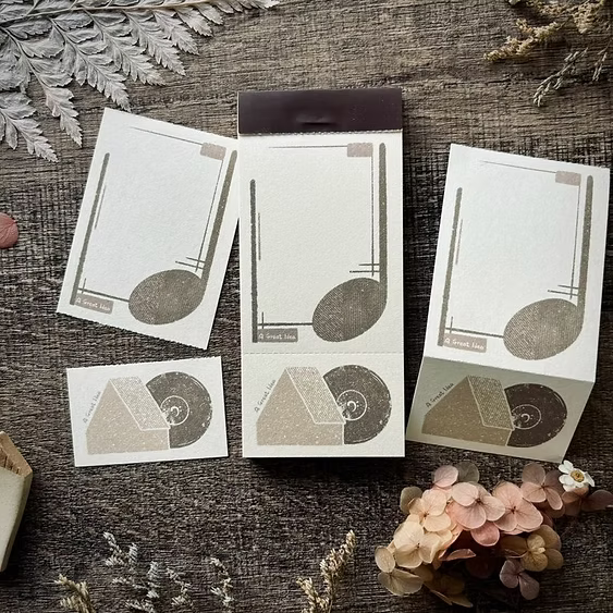 Set of geometric design cards on a textured surface with flowers and leaves.