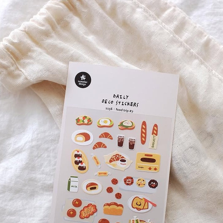 Sheet of decorative stickers with food-themed designs on a white fabric background