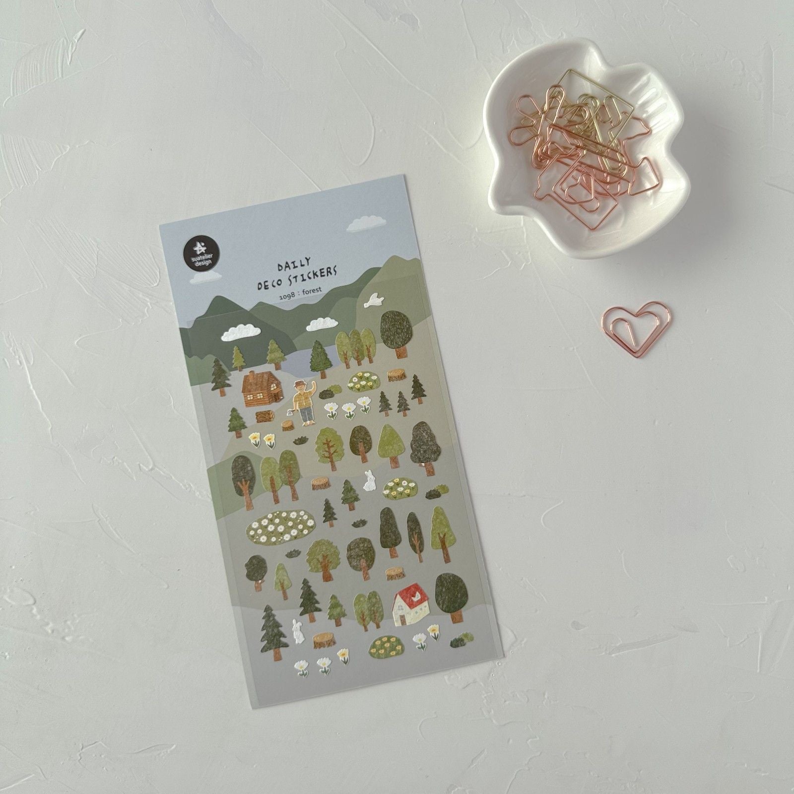Sheet of decorative stickers with nature-themed designs on a white surface with paper clips.