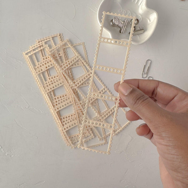 Hand holding delicate cream Frames Vol. 1 lace-style frame cards on a light grey backdrop