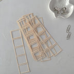 Beige lace trim pieces on a light gray surface with small metal clips.