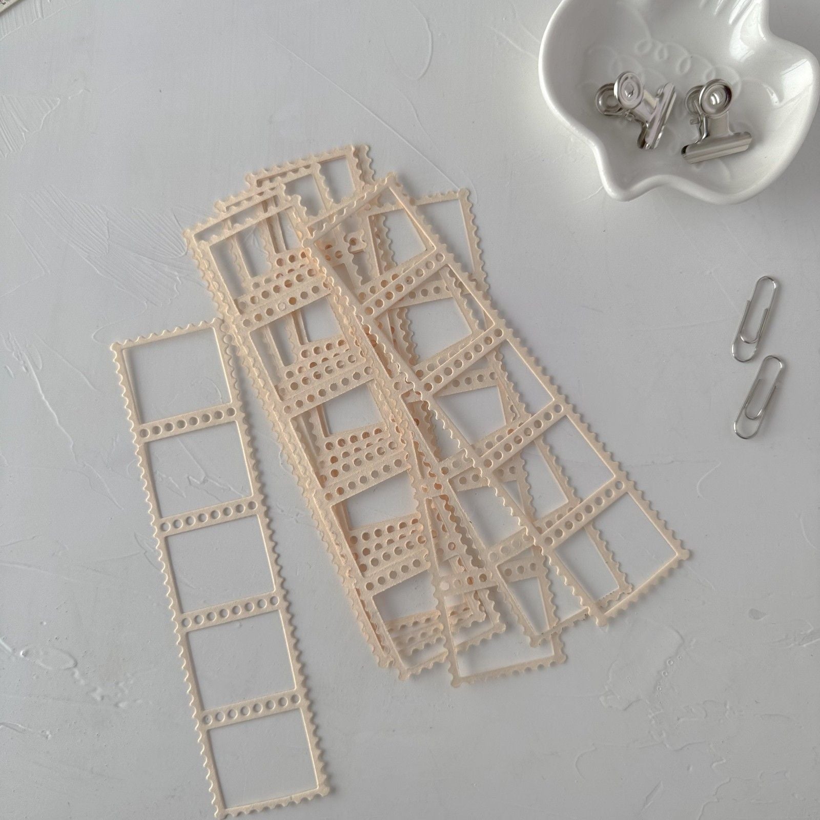 Beige lace trim pieces on a light gray surface with small metal clips.