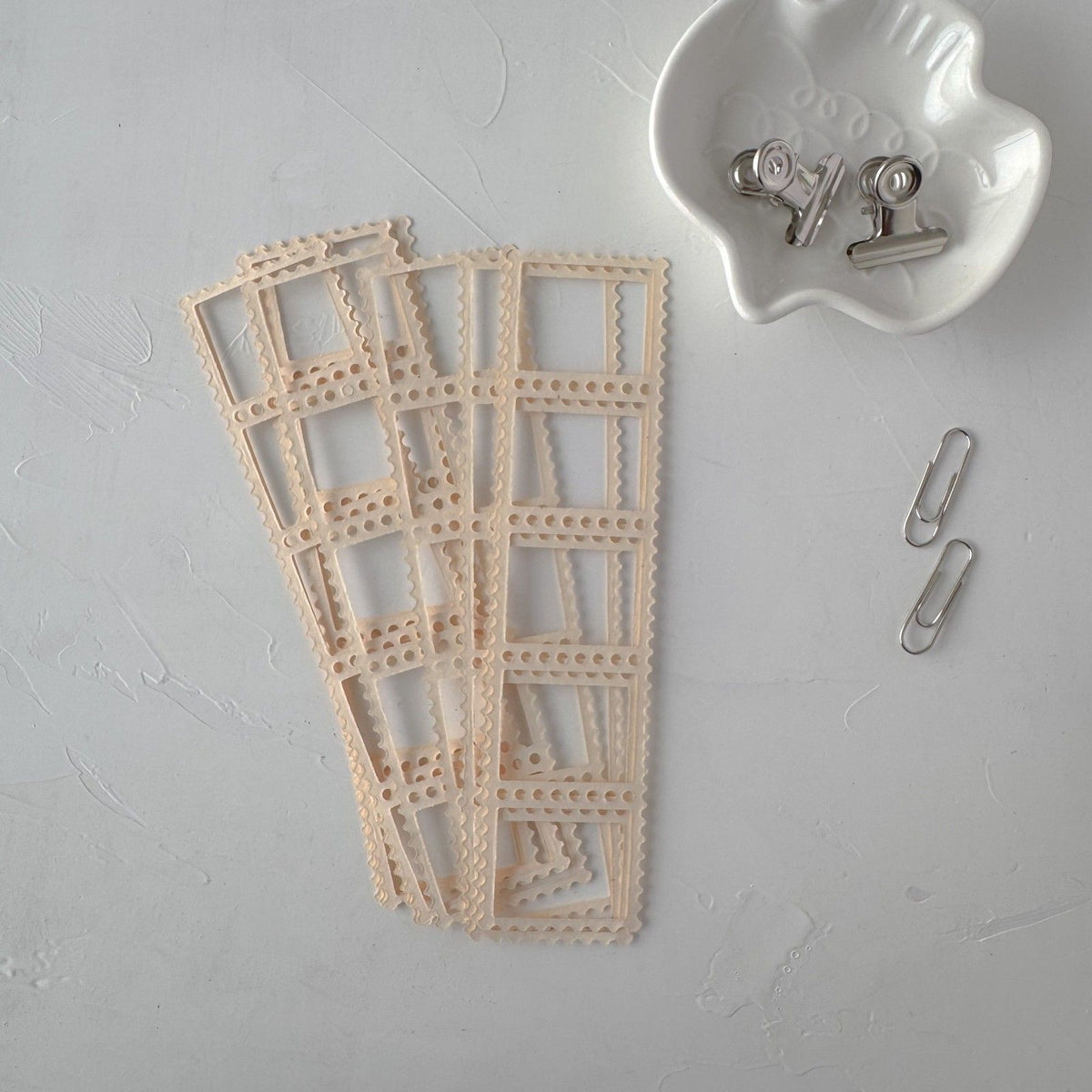 Cream Frames Vol. 1 decorative cutout frame card styled with clips on a grey surface