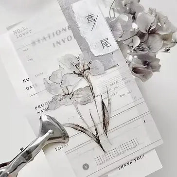 Stationery items including a pen, paper, and dried flowers on a white background