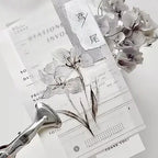 Stationery items including a pen, paper, and dried flowers on a white background