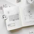 Open notebook with floral stickers and decorative elements on a white surface