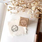 Two wooden stamps on a piece of paper with dried flowers in the background