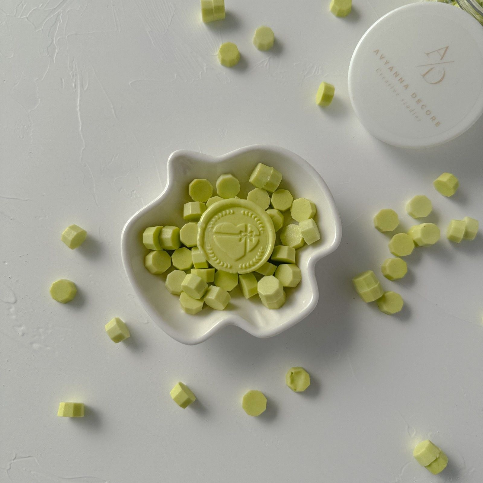 White dish filled with green candy pieces on a light gray background