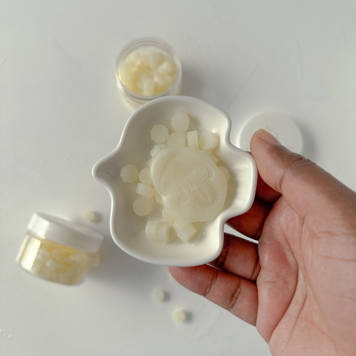 Hand holding a ceramic mold with a turtle-design Frosted Ivory wax seal filled with small round beads