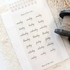 Sheet of days of the week labels with a stamp on a textured surface