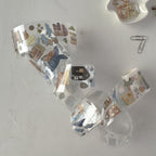 Clear plastic packaging with decorative stickers shaped like a question mark on a light gray surface.